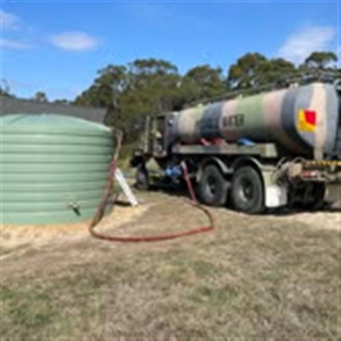 K.R water tanker running a hose to a property water tank